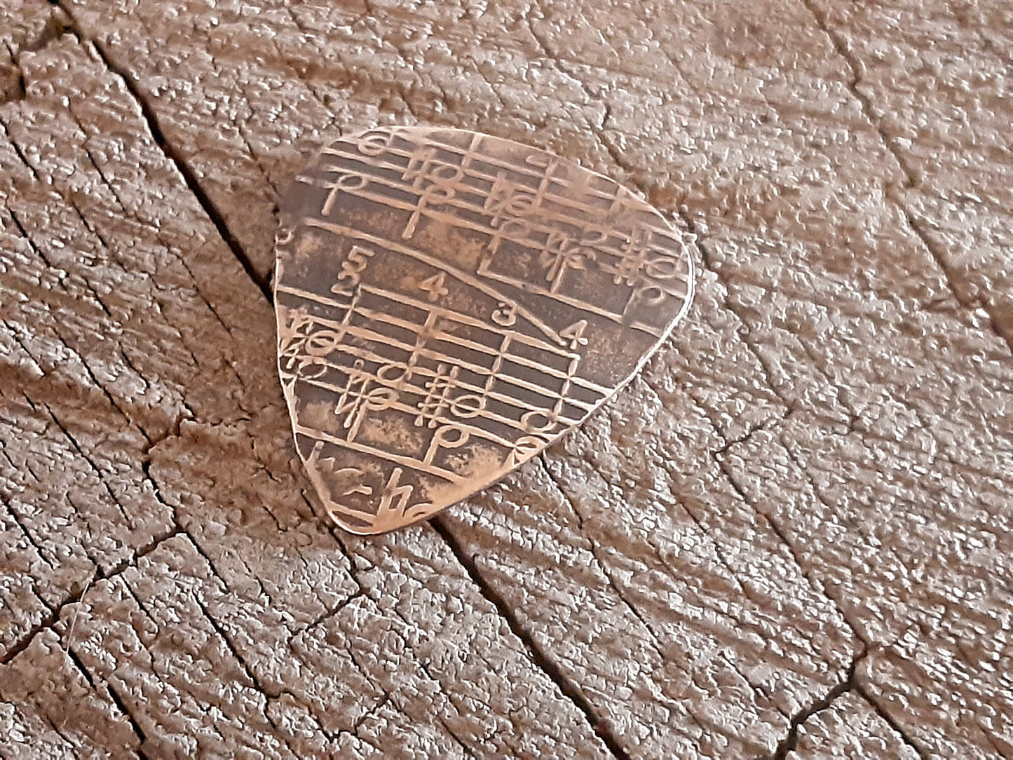 Guitar pick in Bronze with music notes