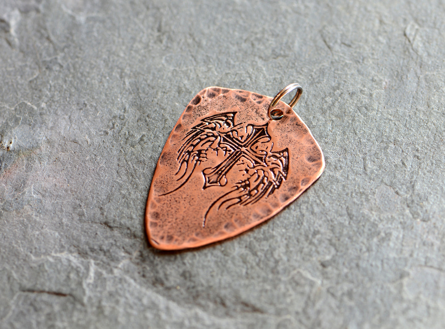 Shield style copper guitar pick necklace featuring a winged cross