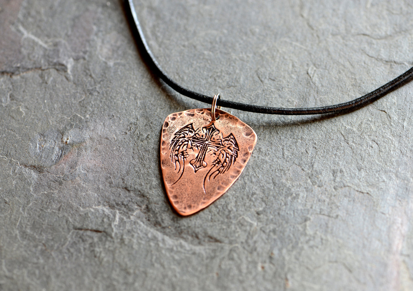 Shield style copper guitar pick necklace featuring a winged cross