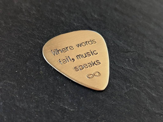 Playable bronze guitar pick stamped with when words fail, music speaks and infinity sign