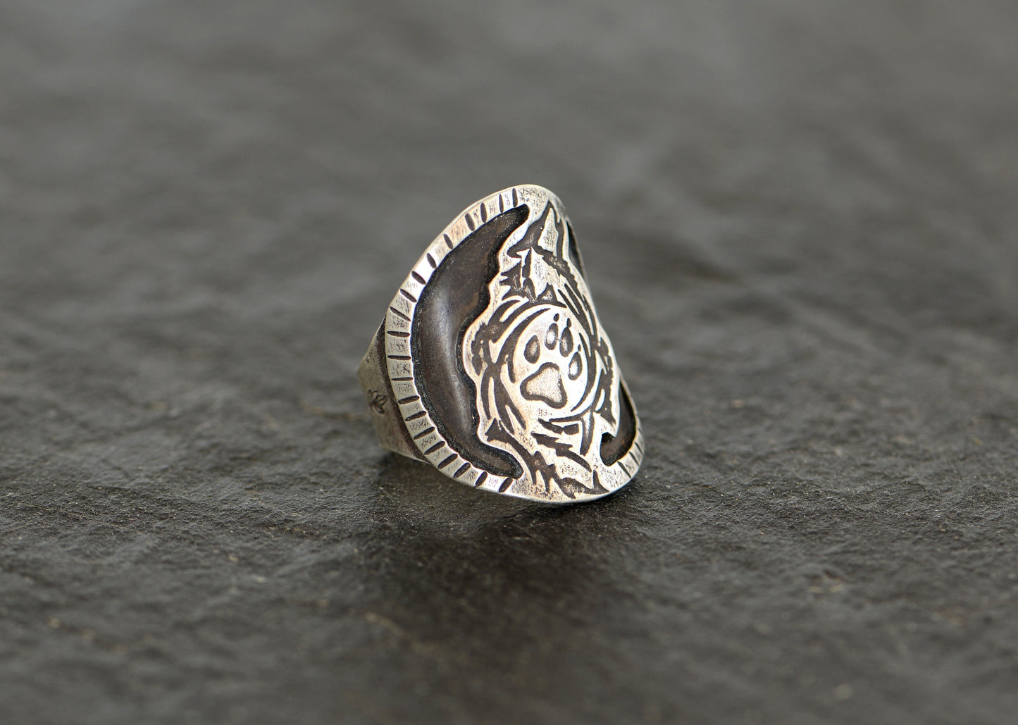 Saddle ring with howling wolf and paw design  in sterling silver