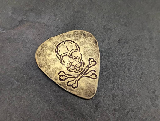 Skull and crossbones on brass guitar pick