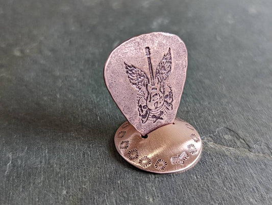 Playable guitar pick with winged guitar and guitar pick stand all in copper